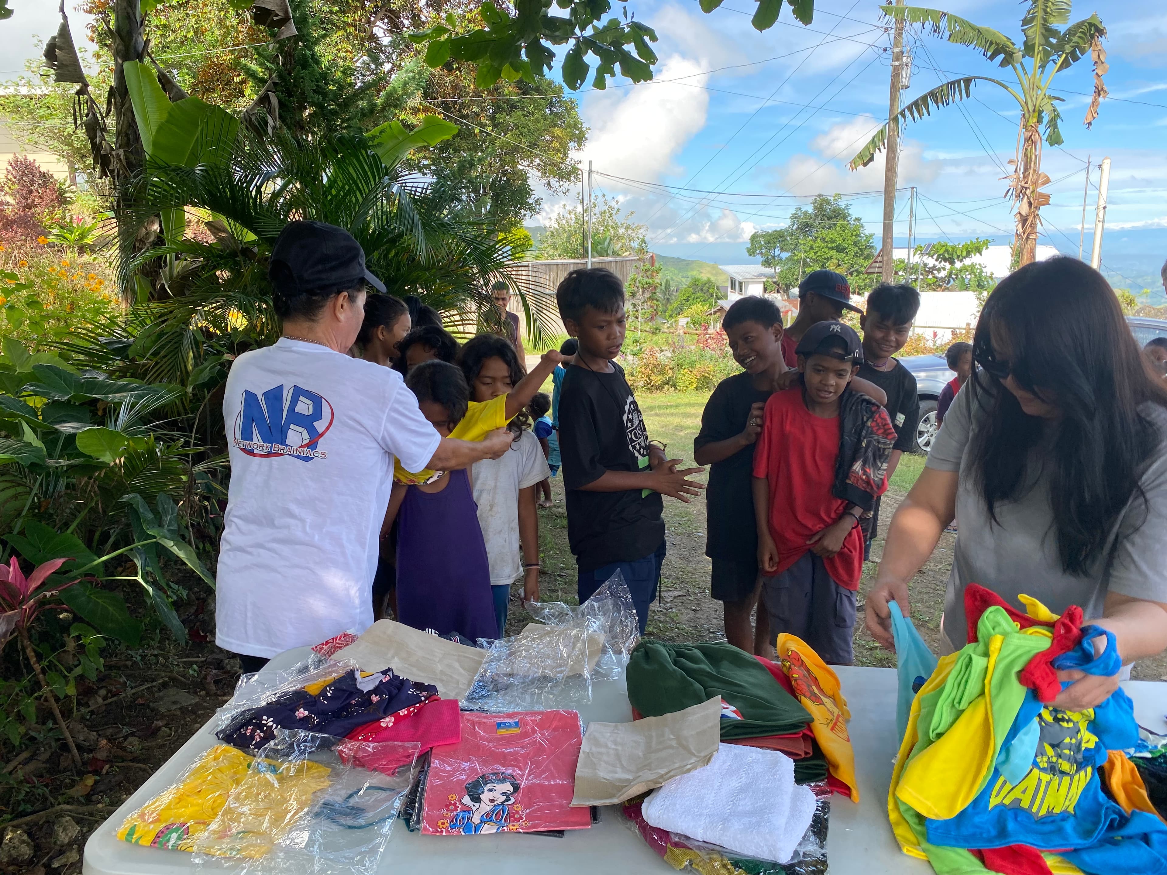 Network Brainiacs volunteer at the clothes table with a line of children